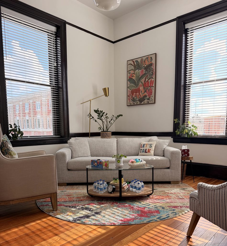 The therapy office interior in Abingdon, Virginia, with a sofa, armchairs, a patterned rug and tall windows